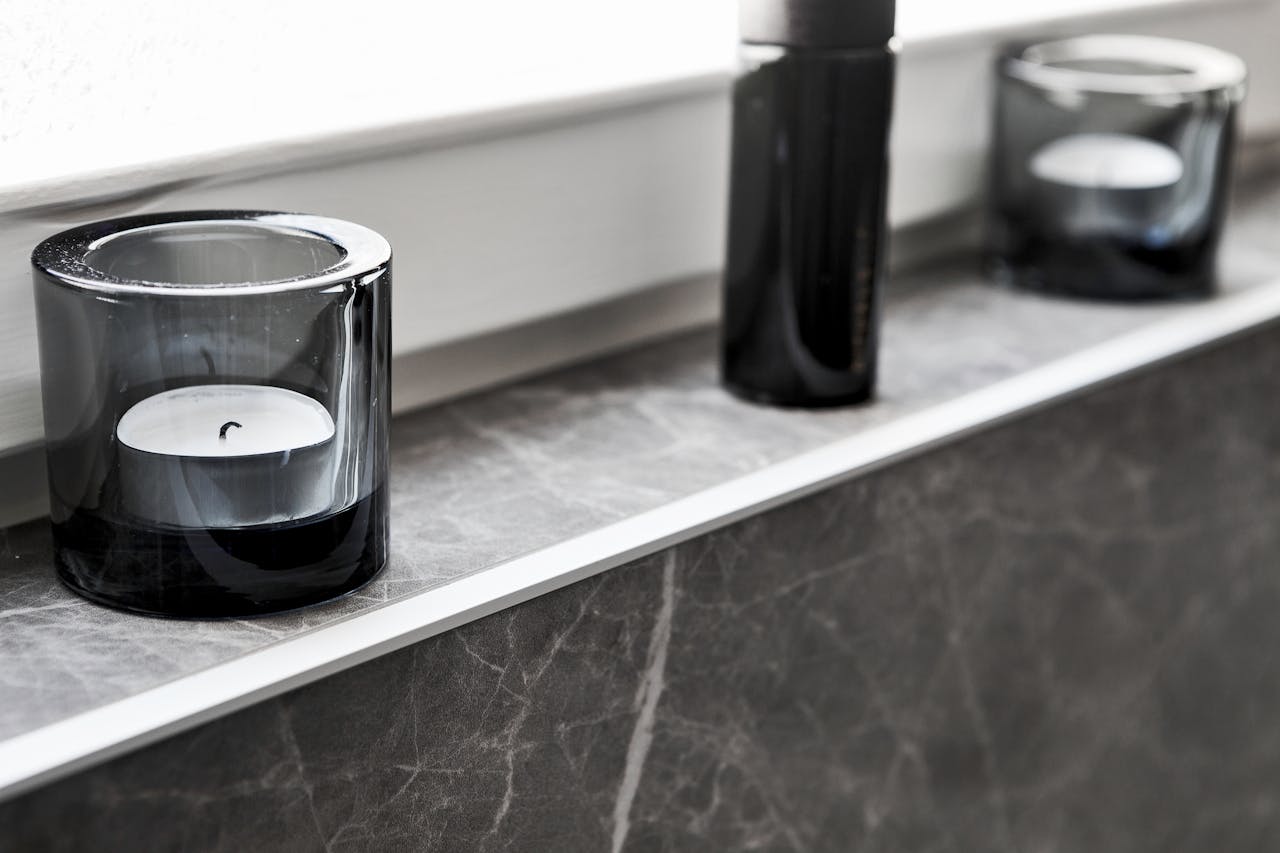 Minimalist marble shelf featuring modern black glass candles in a sleek indoor setting.